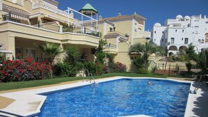 A swimming pool with a clear blue water, surrounded by a tiled deck.