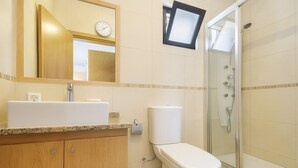 Ein modernes Badezimmer mit Waschbecken, Toilette und Duschkabine aus Glas.