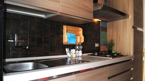 Une cuisine moderne avec des carreaux de couleur sombre, des appareils en acier inoxydable et des meubles de cuisine en bois.
