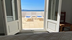 An open balcony with a view of the beach, two white lounge chairs, and a wooden chair. - Paros, Drios Golden Beach: beautiful villa, large private pool, unique sea view (chrisi akti)