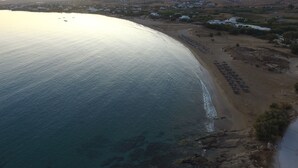A coastal area with a beach, rocky shoreline, and a backdrop of hills. - Paros, Drios Golden Beach: beautiful villa, large private pool, unique sea view (chrisi akti)