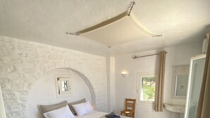 A bedroom with a large bed, a small table, a chair, and a window. - Paros, Drios Golden Beach: beautiful villa, large private pool, unique sea view (chrisi akti)