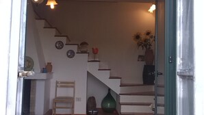 Una escalera conduce a un segundo piso, con una silla y un jarrón verde en la plataforma.