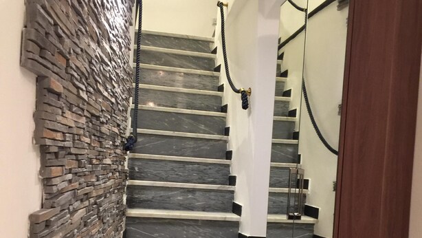 Una escalera con un muro de piedra a un lado y un muro espejado al otro.