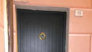 Una puerta negra con pomo y aro de latón.
