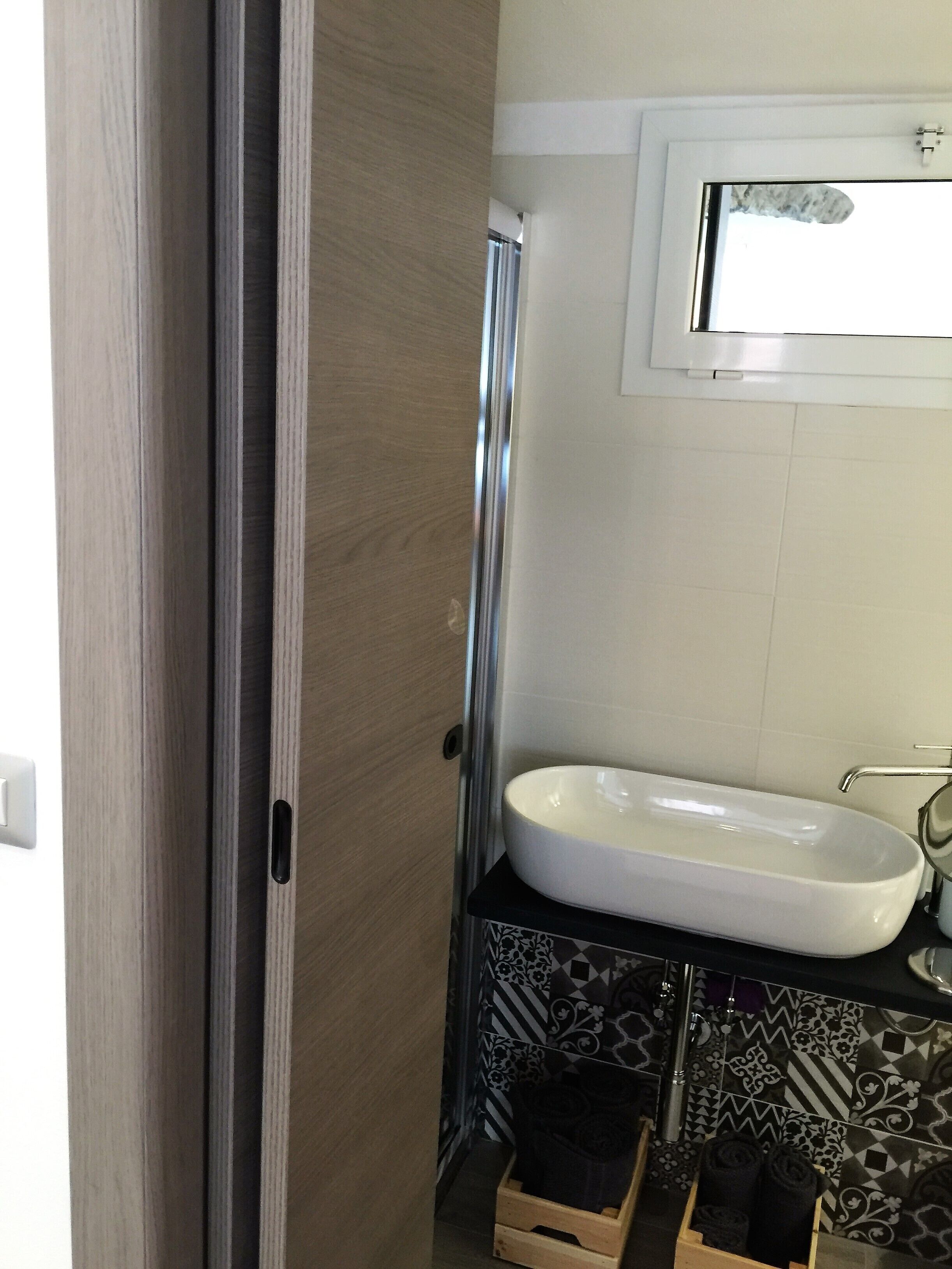 Une salle de bain avec un lavabo blanc, une douche et des carreaux à motifs.