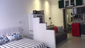 Un espacio habitable compacto con cama, sofá, kitchenette y comedor.