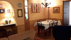 A cozy dining area with a wooden ceiling, a table set for four, and a sofa with patterned cushions. - Casas Rurales Los Arrayanes for 4 people (Ronda)