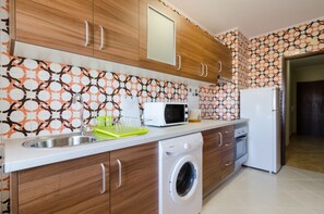 A modern kitchen with wooden cabinets, a built-in washing machine, a microwave, and a refrigerator. - Ocen View 1 Bed Room Flat (Quarteira)