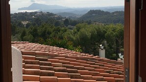 Vista a través d'una porta arqueada de teules de terracota, sobre un paisatge amb vegetació i muntanyes llunyanes.