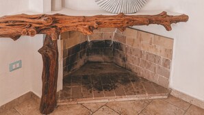 A rustic fireplace with a wooden mantel, a tiled floor, and decorative starfish on the wall.