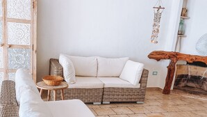 A cozy living area with a white sofa, wicker furniture, and a decorative wall panel.