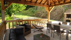 Une terrasse extérieure aménagée avec des meubles en bois, notamment un canapé, des fauteuils et une table.