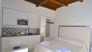 Una habitación de hotel con cama, una mesita, lavamanos y microondas.