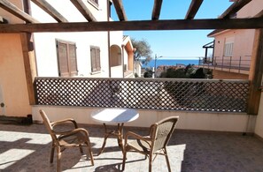 Enjoy the serene sea views from this balcony, featuring a pair of wicker chairs and a small table.