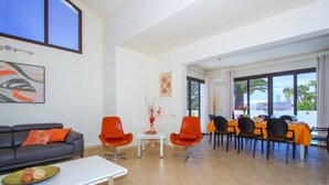 Una sala de estar moderna con un sofá, dos sillones, una mesa de centro y un comedor con mesa y sillas.