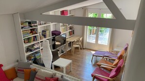 A cozy living room with a sofa, chairs, a TV, and a bookshelf filled with books and games. - Charming villa, heated swimming pool, 4 to 8 persons (Mormoiron)
