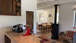 A kitchen with a coffee maker, scale, and a stove. There is a dining area with chairs and a table. - Charming villa, heated swimming pool, 4 to 8 persons (Mormoiron)