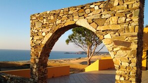 A stone archway leading to a paved area with a view of the sea and a tree. - TORRE DEI CORSARI, THE PEARL OF THE GREEN COAST - IUN Code: P7053 (Arbus)