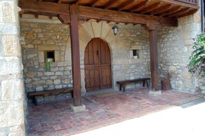 Traditional stone building with a wooden door and stone archway, featuring a wooden ceiling with exposed beams.
