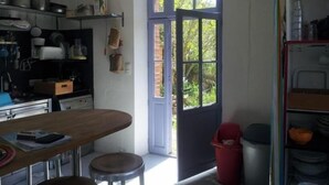 A kitchen with a window, a table, and a red trash bin. - The Port of Millstone, island of Yeu, house with garden pets allowed (L'île-D'yeu)