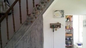 A staircase with a wooden handrail and a stone wall. There is a table with a mug and a bird figurine. - The Port of Millstone, island of Yeu, house with garden pets allowed (L'île-D'yeu)