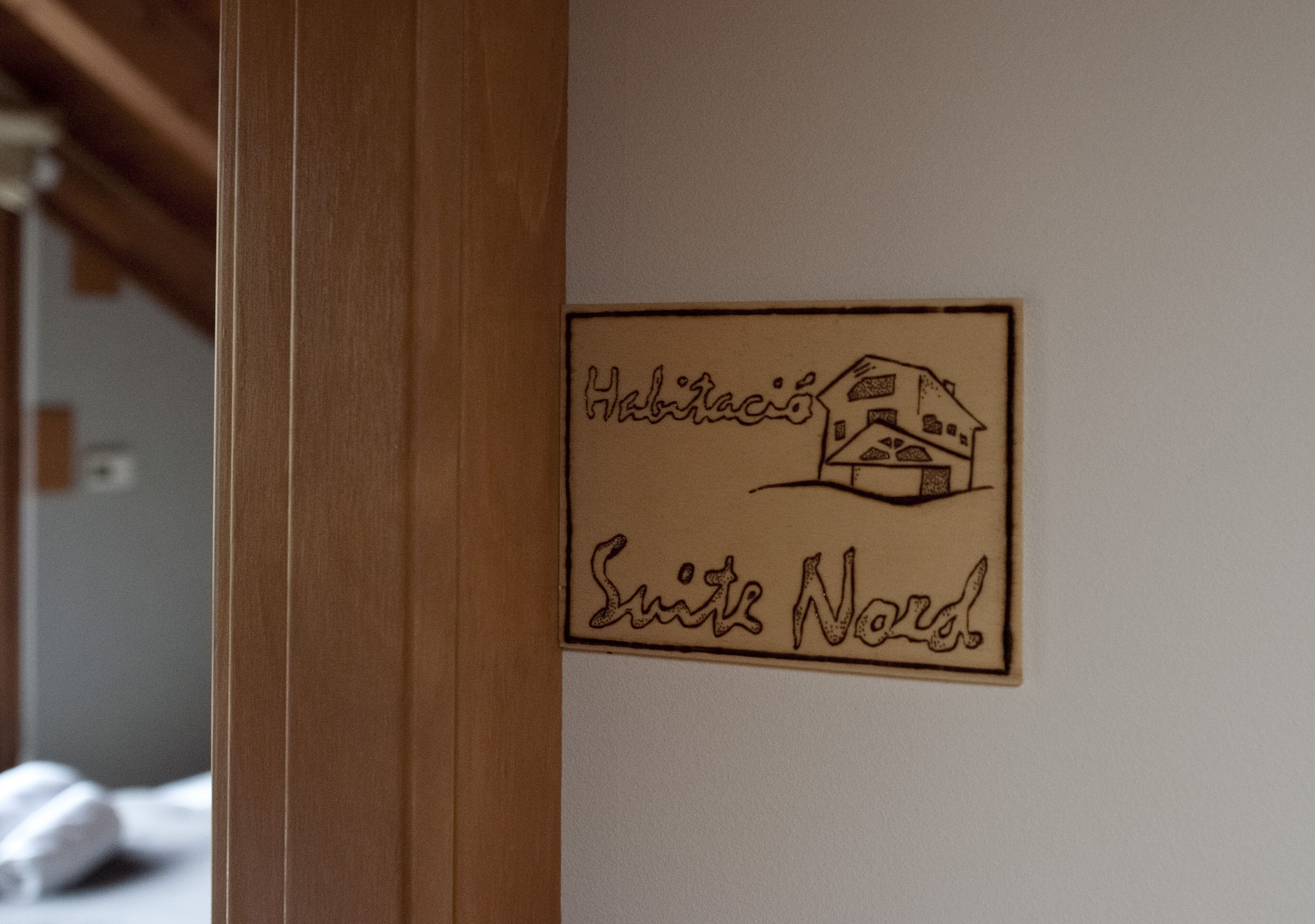 Placa com ilustração de uma casa e texto indicando um número de quarto.