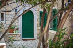 Traditional stone building with a charming arched entrance and lush greenery.