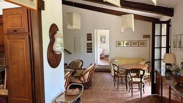 Une cuisine spacieuse avec un coin repas, des meubles en bois, un carrelage au sol et un luminaire suspendu.
