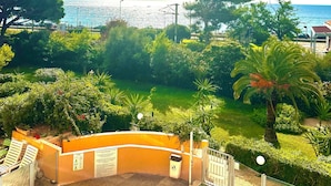 A pool area with a view of the sea, surrounded by greenery and a clear sky. - Cannes - Sea front apartment, beach front, pool, garden, internet, aircon (Cannes)