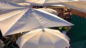 A seaside terrace with white umbrellas and a view of the sea, mountains, and a ship in the distance. - Cannes - Sea front apartment, beach front, pool, garden, internet, aircon (Cannes)