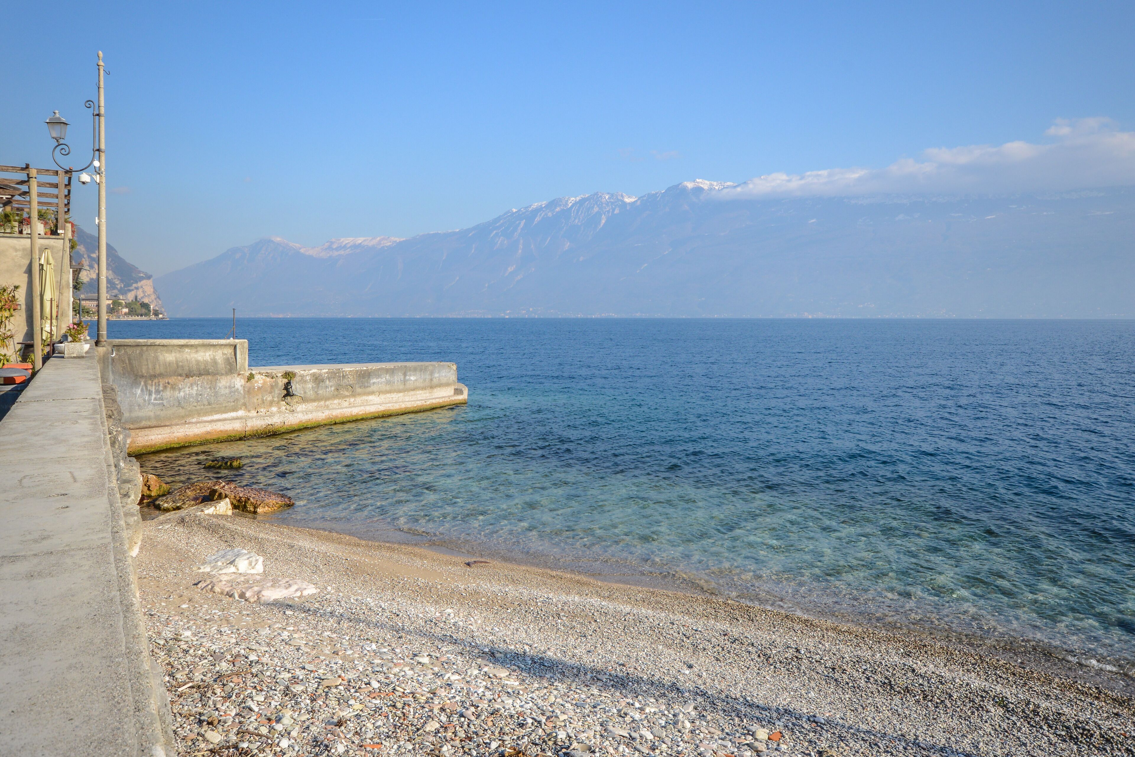 Une plage de galets offrant une vue dégagée sur la mer et les montagnes en arrière-plan.