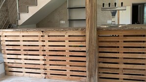 A modern interior with a wooden slatted partition, a staircase with metal railings, and a kitchen area with a stainless steel appliance. - Charming property with its chapel and towers (Lannes)