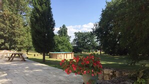 A garden area with a picnic table, a wooden shed, and a potted plant with red flowers. - Charming property with its chapel and towers (Lannes)