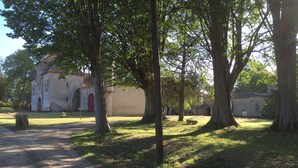 A historic building with a red door, surrounded by trees and a gravel path. - Charming property with its chapel and towers (Lannes)