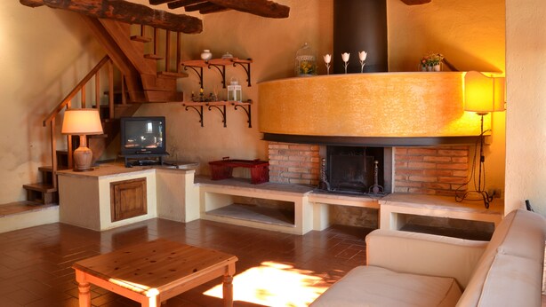 A cozy living room with a fireplace, wooden furniture, and a staircase.