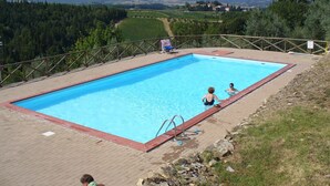 A rectangular swimming pool with a wooden deck and metal ladder, surrounded by a wooden fence.