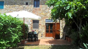 A stone building with a patio area featuring a table and chairs under a white umbrella.