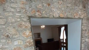 A room with a stone wall, wooden flooring, a fireplace, and a chandelier. - Listed Stone Built Folly with original gothic features (Seaham)