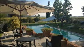 Un espace piscine extérieur avec des chaises longues, une table et des plantes en pot.