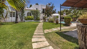 A well-maintained garden with a stone pathway leading to a white building with a tiled roof. - CALA D'OR STUNNING PRIVATE VILLA + BUNGALOW 10 MIN WALK TO BEACH! (Cala d'or)
