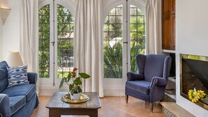 A living room with a blue armchair, a sofa, a coffee table with a plant, and a fireplace. - CALA D'OR STUNNING PRIVATE VILLA + BUNGALOW 10 MIN WALK TO BEACH! (Cala d'or)