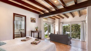 A bedroom with a bed, a mirror, a painting, a small table, and a view of the outside. - CALA D'OR STUNNING PRIVATE VILLA + BUNGALOW 10 MIN WALK TO BEACH! (Cala d'or)