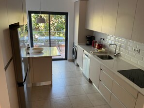 A modern kitchen with a built-in dishwasher, a sink, and a coffee maker.