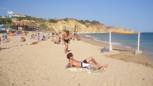 A beach scene with people sunbathing and swimming. - Luxury 2 Bed Apartment with pool near to beach (Porto De Mos)