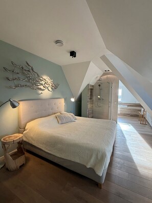 A bedroom with a large bed, a nightstand, a wall-mounted light, and a ceiling light.