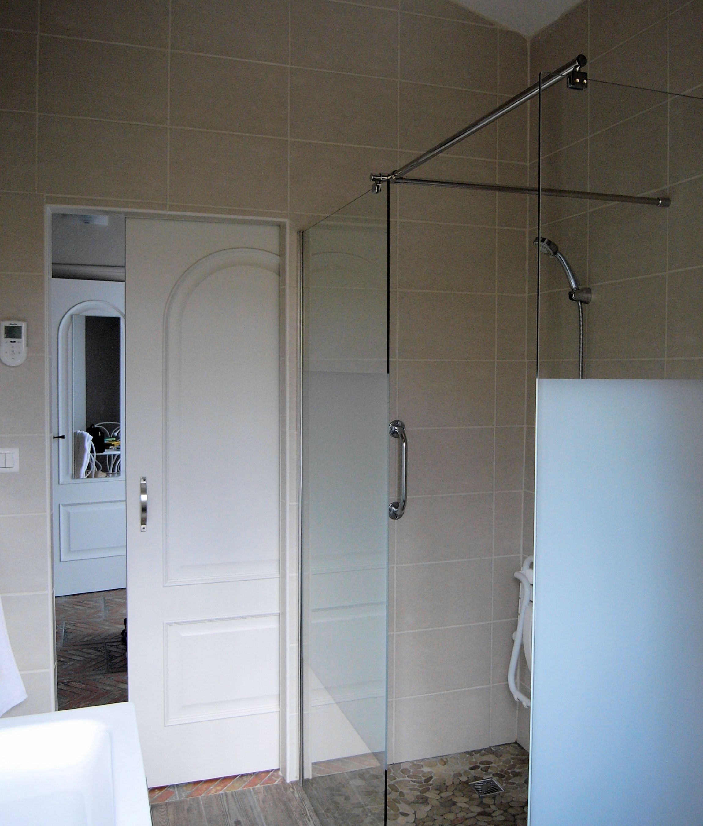 A bathroom with a glass shower door, a white toilet, and a white sink.