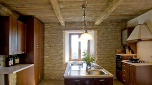 Una cocina rústica con armarios de madera, pared de piedra, lámpara colgante y una ventana.