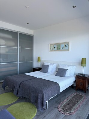 A modern bedroom with a large bed, two bedside tables, a sliding glass door, and a framed bird illustration on the wall. -  AtlanticWindow - Modern House, Stunning View (São Roque do Pico)