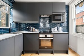 A modern kitchen with dark cabinetry, a Bosch microwave, a Samsung oven, and a coffee maker. - PRIVATE APARTMENT - HEART OF SHOREDITCH (London)